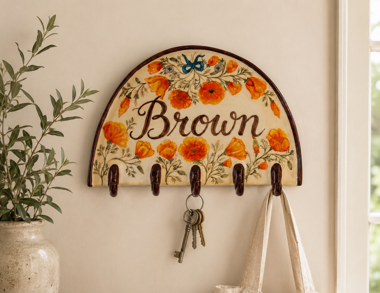 Personalized ceramic key holder with orange floral pattern and dark wall hooks