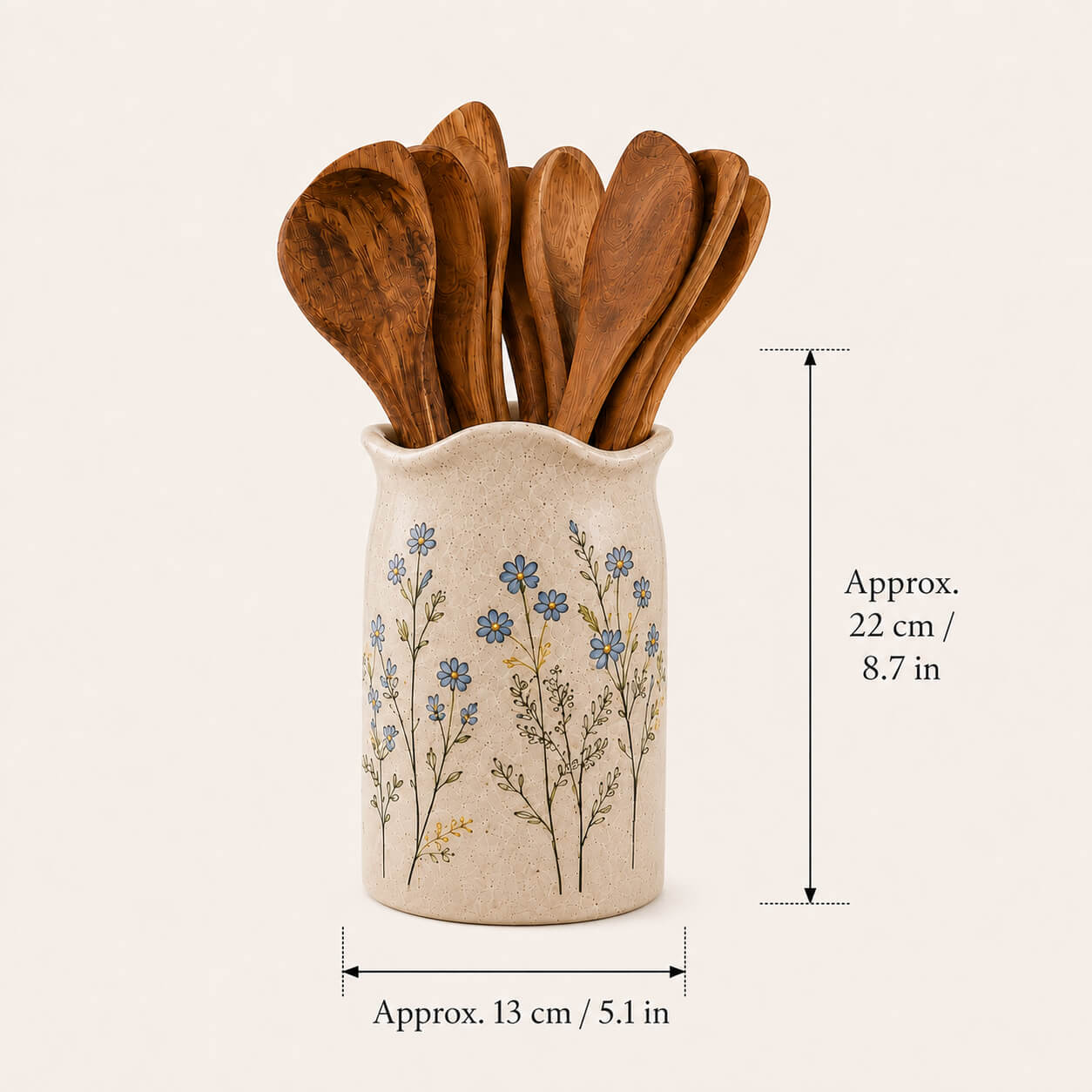 A beige ceramic utensil holder with blue floral illustrations, containing several wooden spoons, shown on a light cream background with dimension lines indicating approximately 22 cm in height and 13 cm in width.