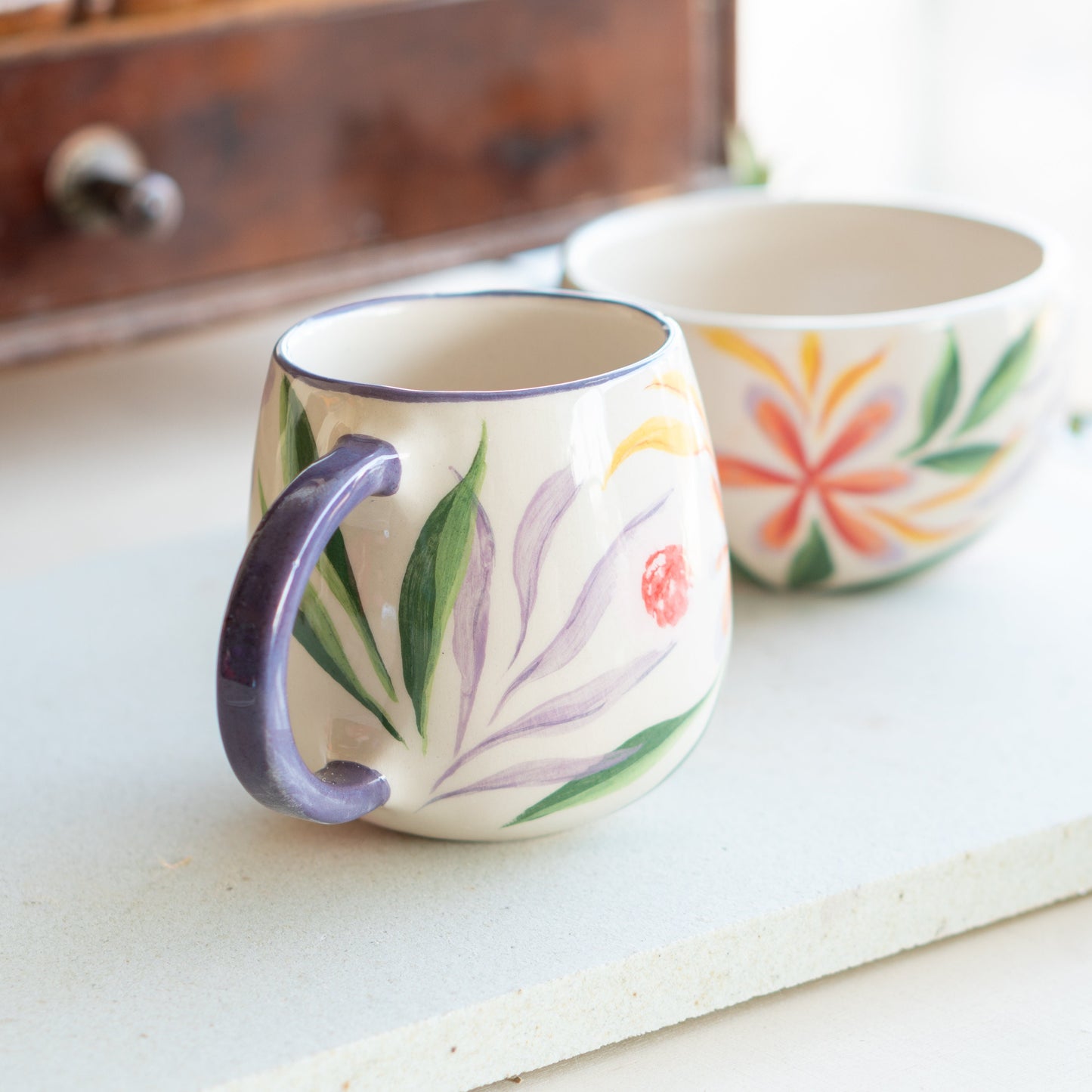 Pair of Blossom Mugs on a kitchen counter, with the foreground mug's bright floral design commanding attention.